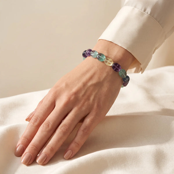 Bracelet fluorite porté au poignet d'une femme, pierres roulées translucides violet, vert et bleu