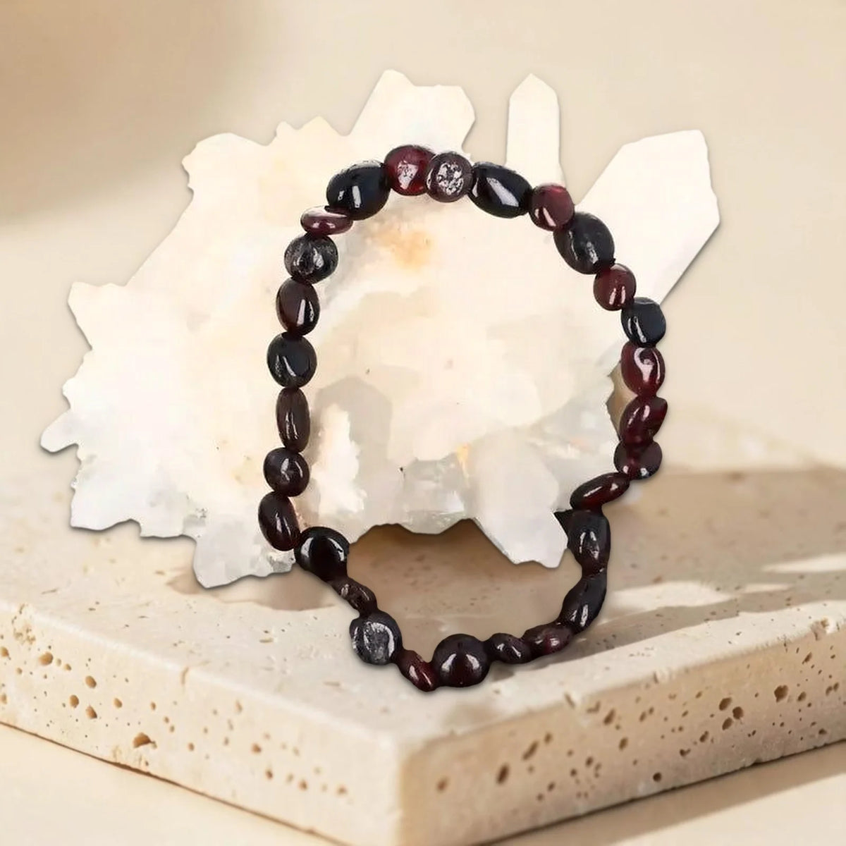 Photo réelle du bracelet grenat en pierre roulée naturelle sur travertin beige