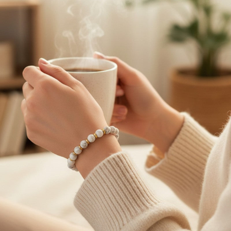 Bracelet Howlite blanche AURA® porté au poignet, bracelet fin doré en pierre naturelle