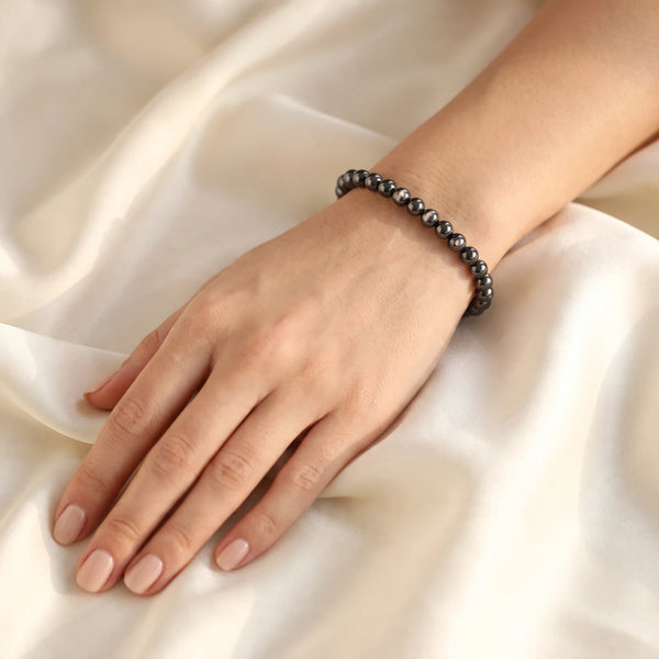 Bracelet hypersthène femme en perles fines de 6 mm, pierre noire aux reflets argentés portée au poignet