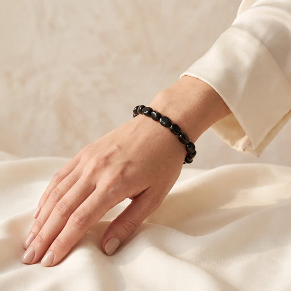 Bracelet hypersthène porté au poignet d'une femme, pierres roulées noir brillant