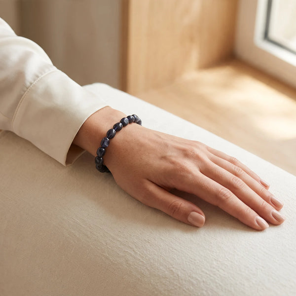 Bracelet iolite porté au poignet d'une femme, pierres roulées bleu nuit et violet