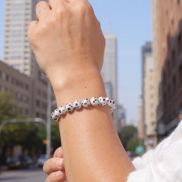 Bracelet en Jaspe Dalmatien vu au poignet en extérieur urbain — perles beige crème à taches noires