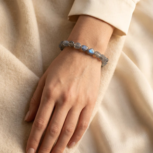 Bracelet labradorite porté au poignet d'une femme, pierres roulées grises à reflets bleus