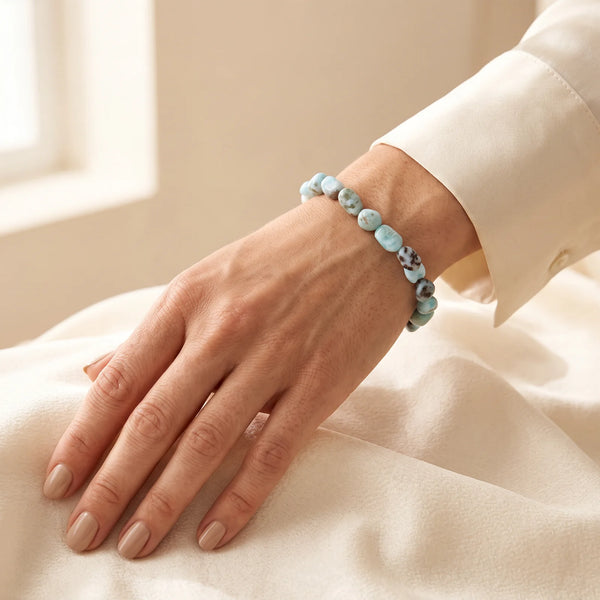 Bracelet larimar porté par une femme, pierres roulées bleu ciel marbrées