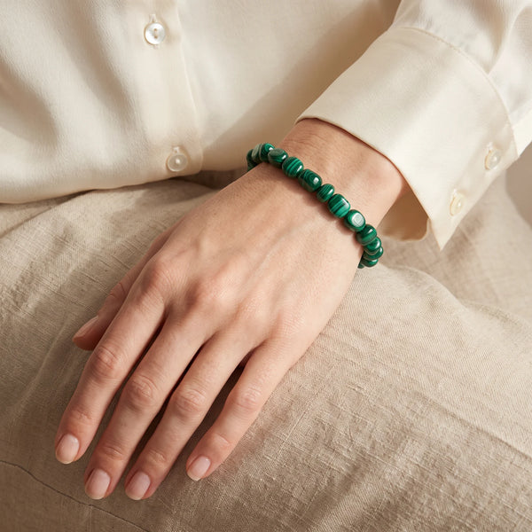 Bracelet en malachite porté par une femme, pierres roulées vert émeraude au poignet