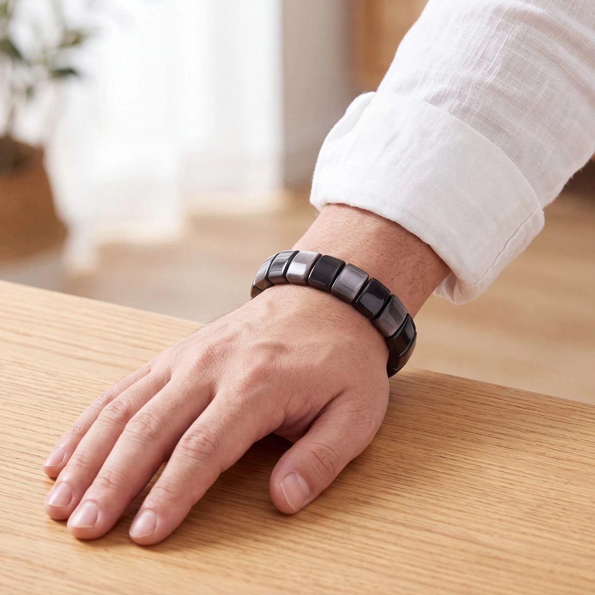 Bracelet obsidienne homme en plaques de 14 mm au poignet, pierre noire à reflet argenté sur élastique