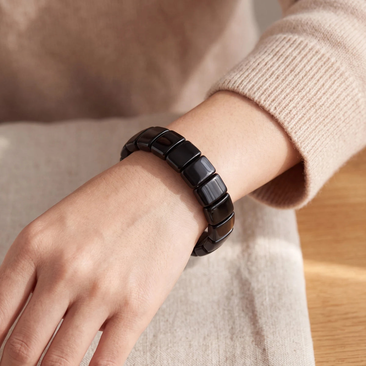 Bracelet obsidienne noire porté au poignet d'une femme, plaques noires polies
