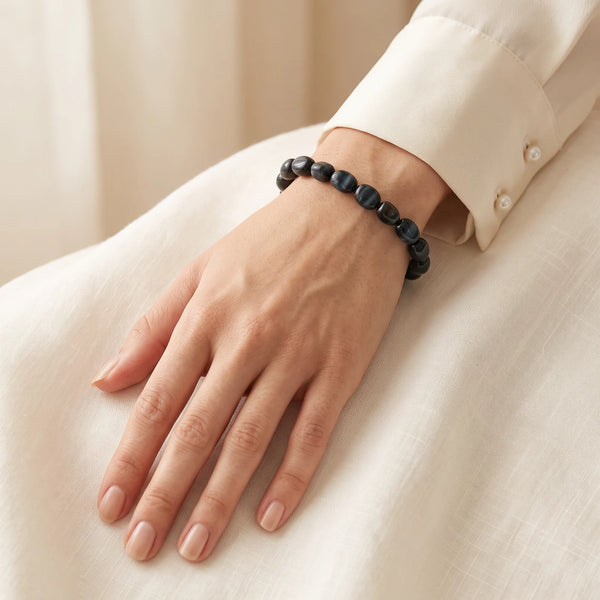 Bracelet œil de faucon porté au poignet d'une femme, pierres roulées aux reflets chatoyants