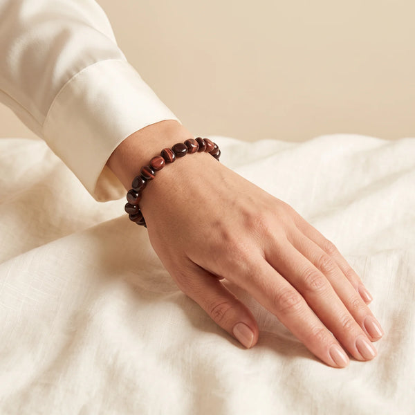 Bracelet œil de taureau porté par une femme, pierre naturelle rouge acajou aux reflets soyeux
