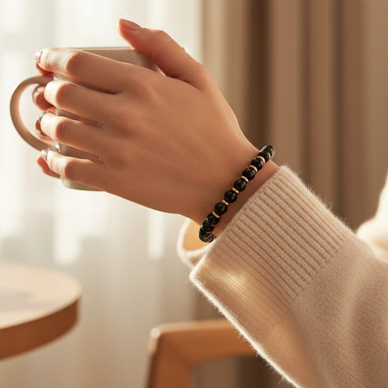 Bracelet Onyx noir AURA® porté au poignet, bracelet fin doré en pierre naturelle