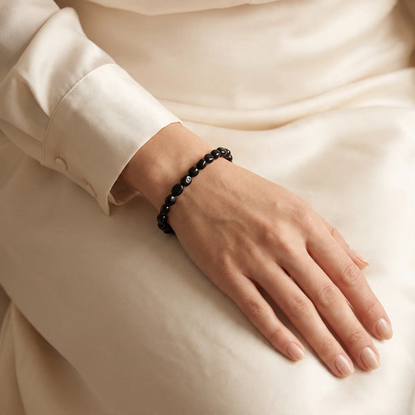 Bracelet onyx noir porté au poignet d'une femme, pierres roulées polies, bijou élégant