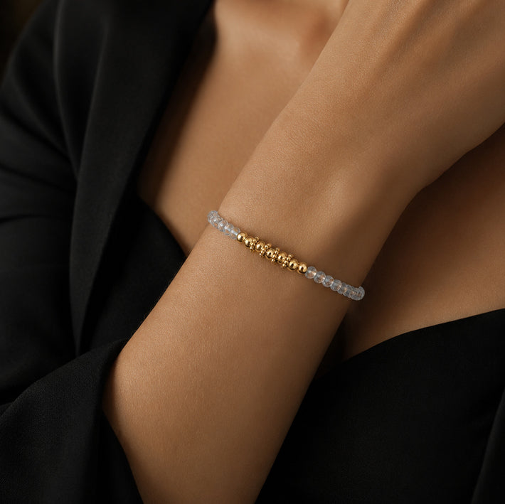 Bracelet pierre aigue-marine FINA® porté au poignet d'une femme, perles facettées et perles dorées