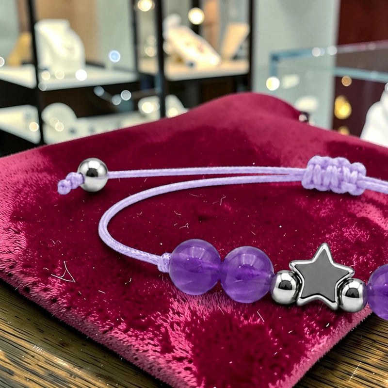 Gros plan du bracelet améthyste ÉTOILE®, breloque étoile en acier argenté entre les perles violettes