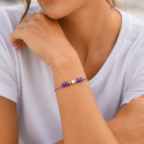 Bracelet pierre naturelle améthyste porté au poignet d'une femme, cordon violet et étoile argentée ÉTOILE®