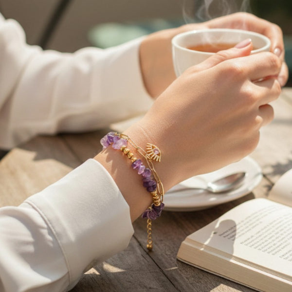 Bracelet mauvais œil en améthyste porté au poignet d'une femme, pierres violettes et chaîne dorée OCULUS®