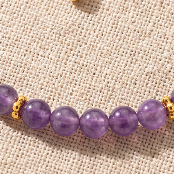 Gros plan sur les perles d'améthyste de 4 mm et les rondelles fleurs dorées du bracelet ORÉLIA®