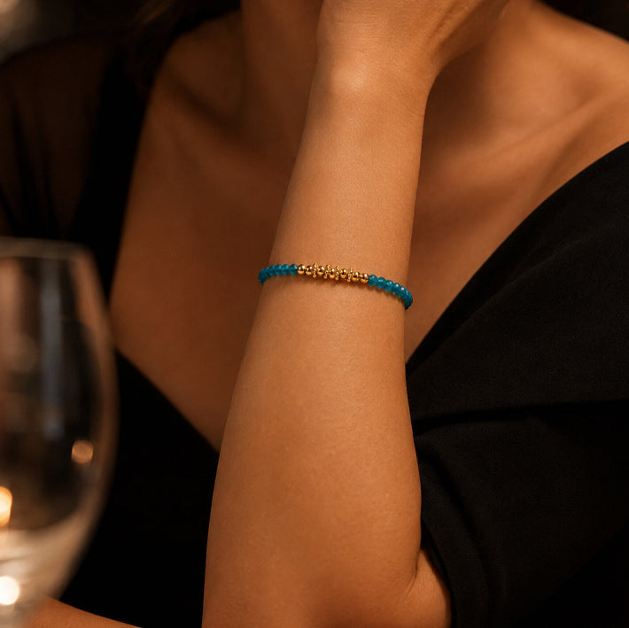 Bracelet pierre apatite bleue FINA® porté au poignet d'une femme, perles facettées et perles dorées