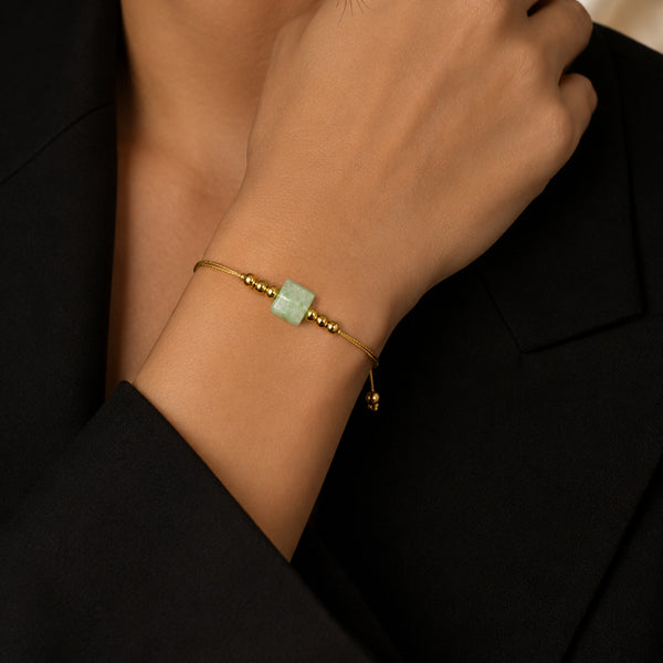 Bracelet pierre naturelle aventurine verte porté au poignet d'une femme, cube vert et cordon doré CUBE®