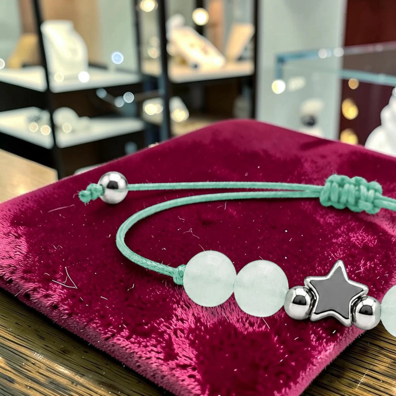 Gros plan du bracelet aventurine verte ÉTOILE®, breloque étoile en acier argenté entre les perles vertes