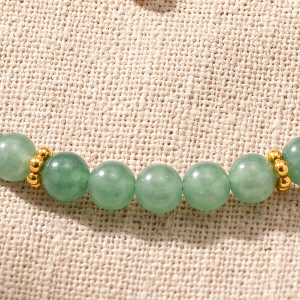 Gros plan sur les perles d'aventurine verte de 4 mm et les rondelles fleurs dorées du bracelet ORÉLIA®