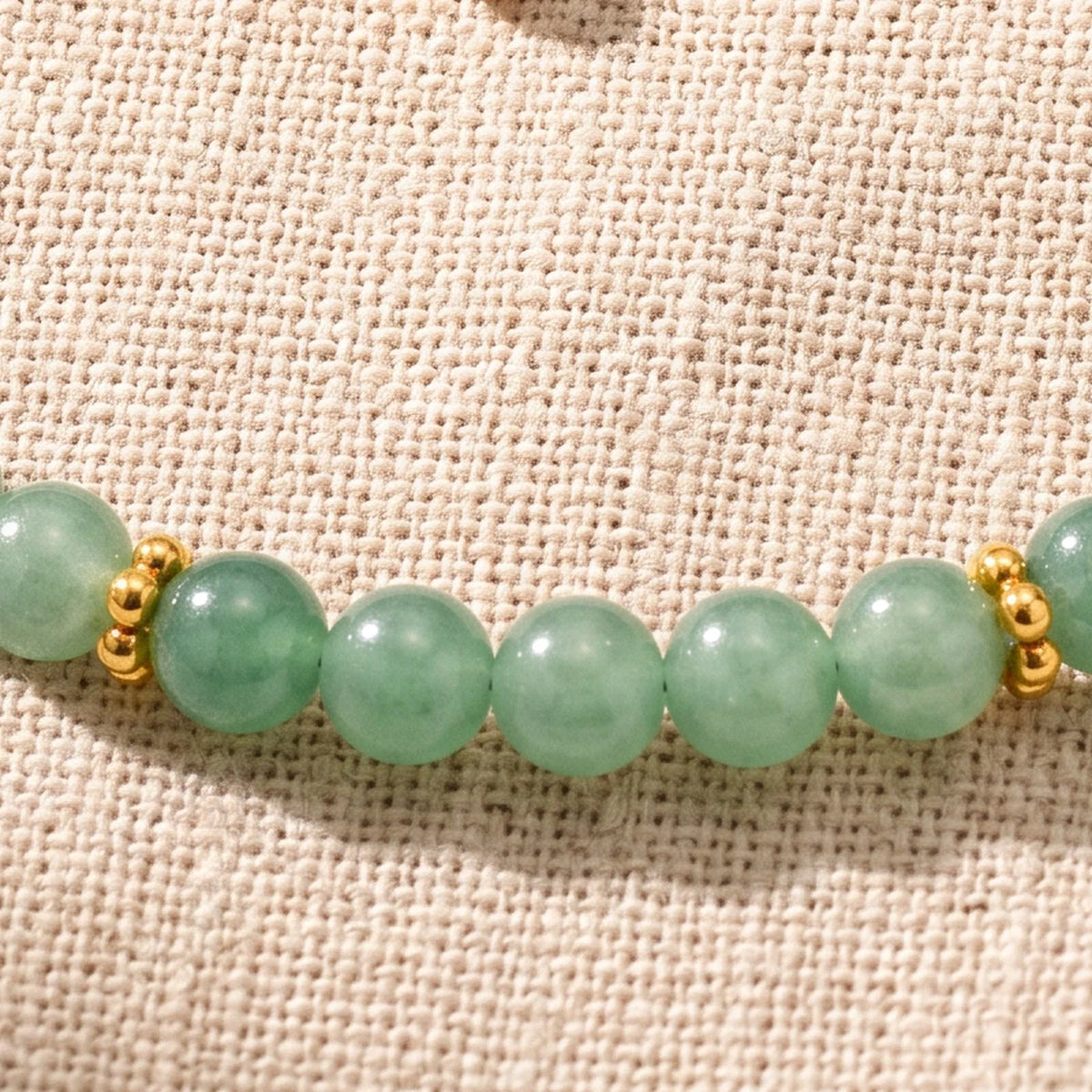 Gros plan sur les perles d'aventurine verte de 4 mm et les rondelles fleurs dorées du bracelet ORÉLIA®