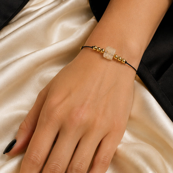 Bracelet pierre naturelle cornaline porté au poignet d'une femme, cube orange et cordon doré CUBE®