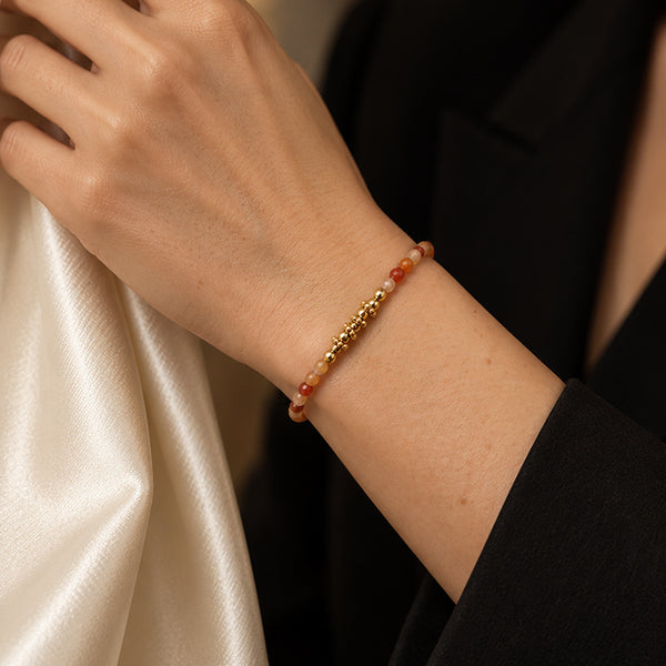 Bracelet pierre cornaline FINA® porté au poignet d'une femme, perles facettées et perles dorées