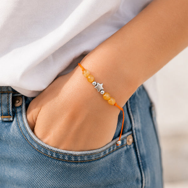 Bracelet pierre naturelle cornaline porté au poignet d'une femme, cordon orange et étoile argentée ÉTOILE®