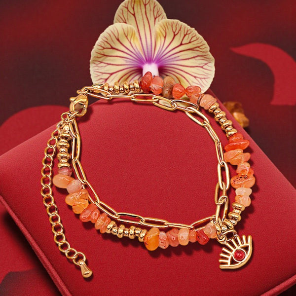 Bracelet mauvais œil en cornaline porté au poignet d'une femme, pierres orange et chaîne dorée OCULUS®