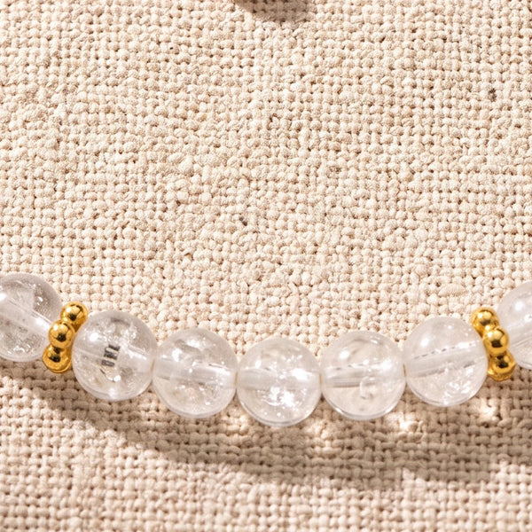 Gros plan sur les perles de cristal de roche de 4 mm et les rondelles fleurs dorées du bracelet ORÉLIA®