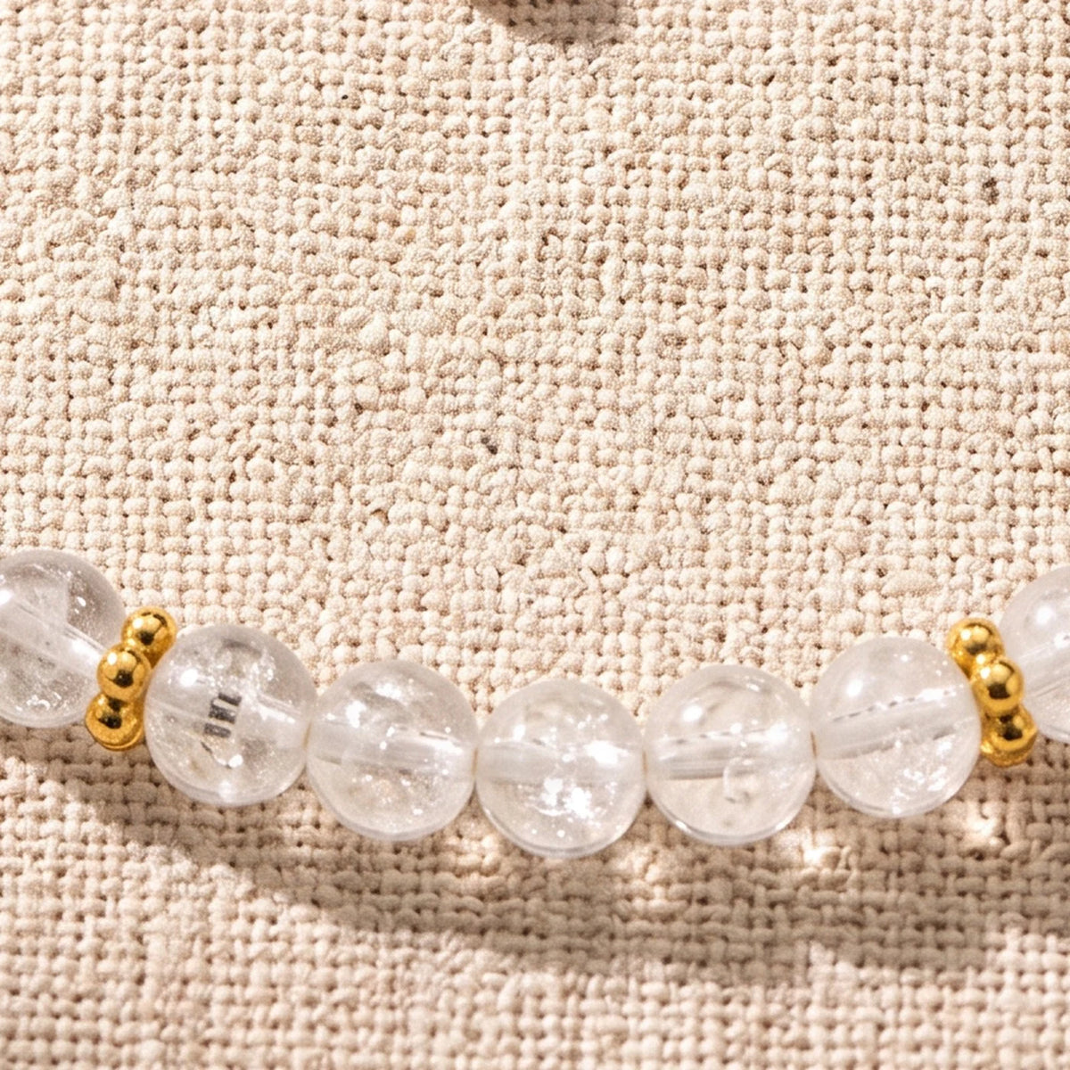 Gros plan sur les perles de cristal de roche de 4 mm et les rondelles fleurs dorées du bracelet ORÉLIA®