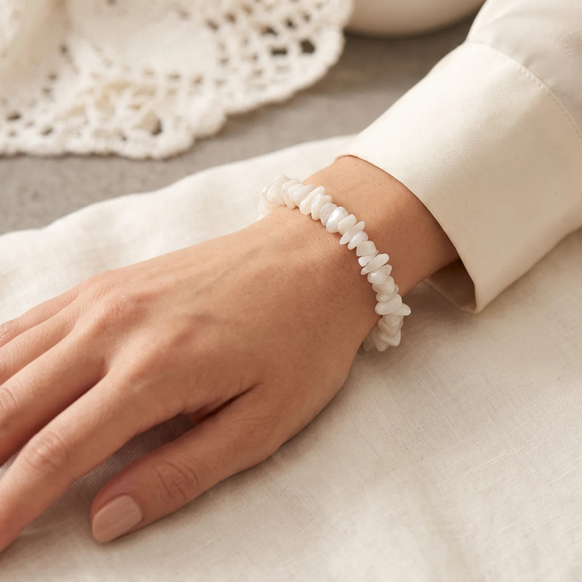 Bracelet pierre de lune baroque porté au poignet d'une femme, reflets laiteux