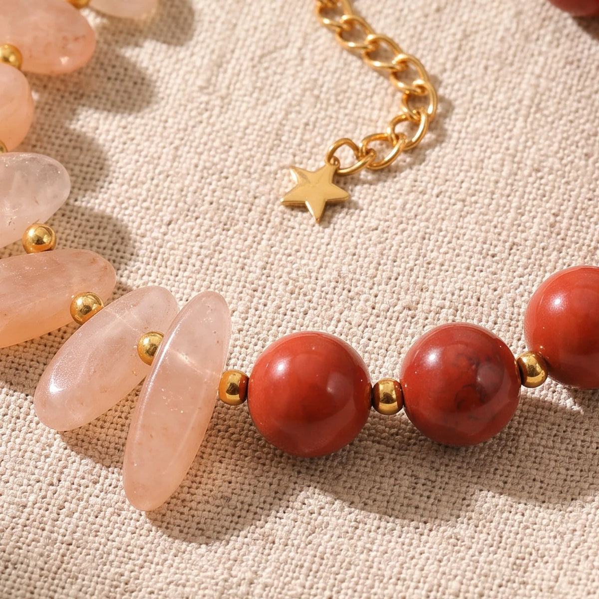 Gros plan sur les pierres du bracelet en pierre de lune rose DUALIA®, perles dorées et breloque étoile