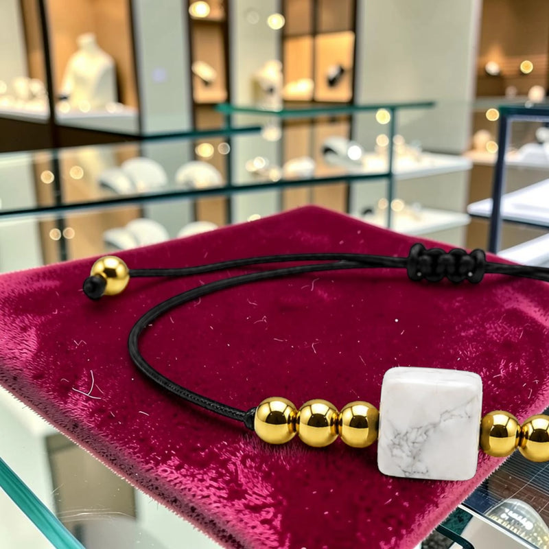 Gros plan de la pierre cube 8 mm en howlite blanche du bracelet cordon doré CUBE®, veines grises sur fond blanc