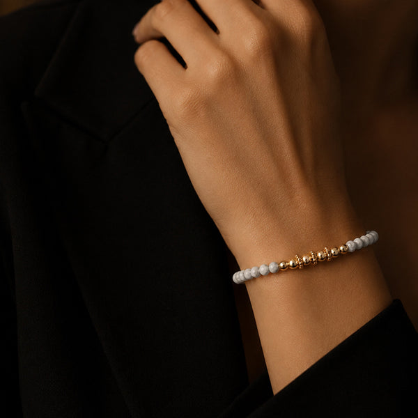 Bracelet pierre howlite blanche FINA® porté au poignet d'une femme, perles facettées et perles dorées