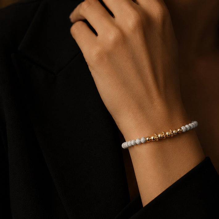 Bracelet pierre howlite blanche FINA® porté au poignet d'une femme, perles facettées et perles dorées