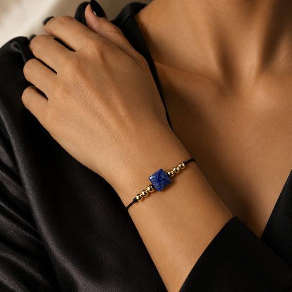 Bracelet pierre naturelle lapis-lazuli porté au poignet d'une femme, cube bleu nuit et cordon doré CUBE®