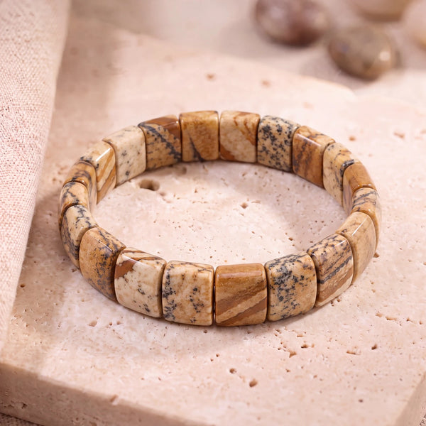 Bracelet jaspe paysage homme en plaques plates de 14 mm aux motifs beige et brun, sur une dalle de travertin