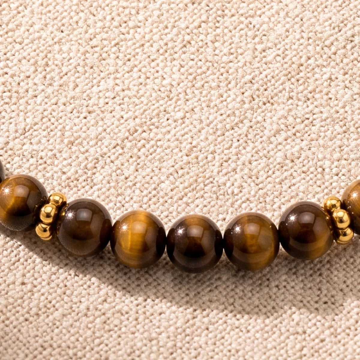 Gros plan sur les perles d'œil de tigre de 4 mm et les rondelles fleurs dorées du bracelet ORÉLIA®