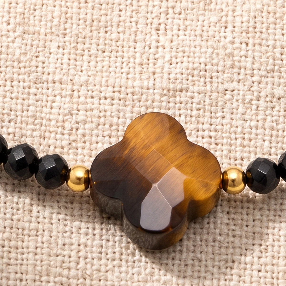 Gros plan sur le trèfle facetté du bracelet œil de tigre femme TRÉFLIA®, perles de 3 mm et perles dorées