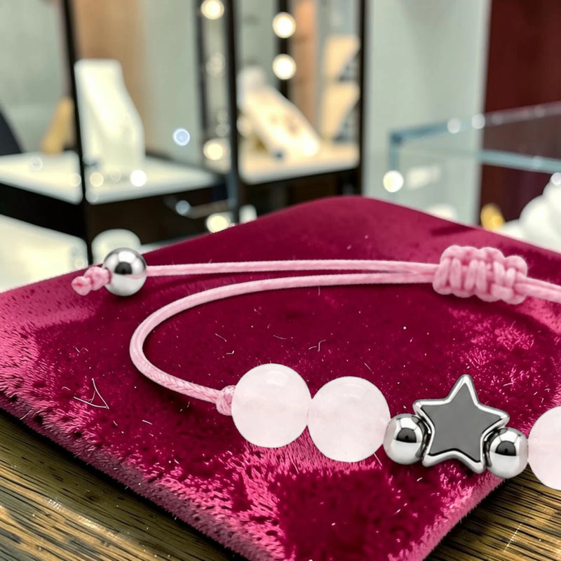 Gros plan du bracelet quartz rose ÉTOILE®, breloque étoile en acier argenté entre les perles rose pâle