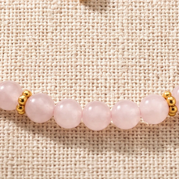 Gros plan sur les perles de quartz rose de 4 mm et les rondelles fleurs dorées du bracelet ORÉLIA®