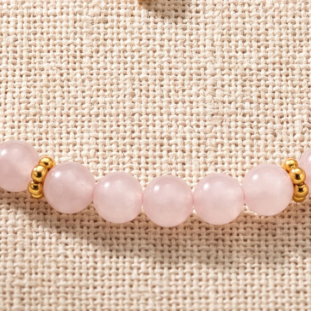 Gros plan sur les perles de quartz rose de 4 mm et les rondelles fleurs dorées du bracelet ORÉLIA®