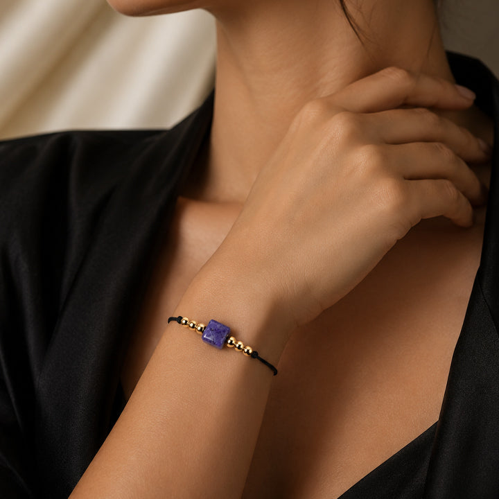 Bracelet pierre naturelle sodalite porté au poignet d'une femme, cube bleu roi et cordon doré CUBE®