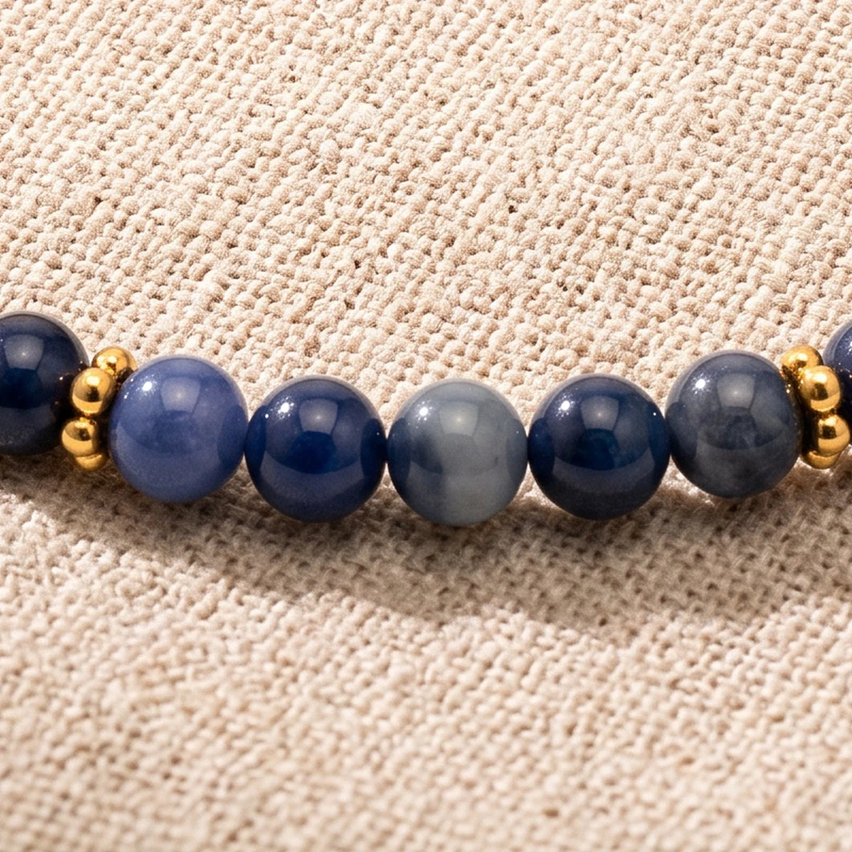 Gros plan sur les perles de sodalite de 4 mm et les rondelles fleurs dorées du bracelet ORÉLIA®