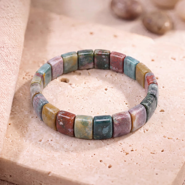 Bracelet agate indienne homme en plaques de 14 mm aux tons vert et rouille, posé sur une dalle de travertin