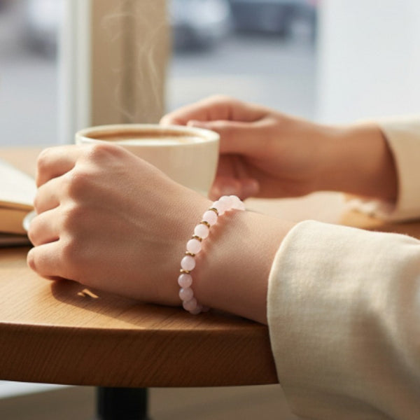 Bracelet Quartz rose AURA® porté au poignet, bracelet fin doré en pierre naturelle