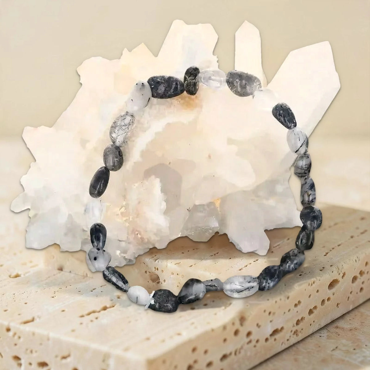 Bracelet en quartz à tourmaline noire, galets roulés photographiés sur un amas de cristal