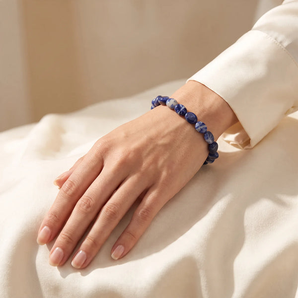 Bracelet sodalite porté au poignet d'une femme, pierres roulées bleu nuit
